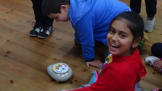 Alunos brincam com um robot.