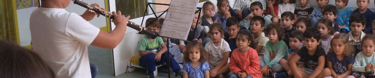 Alunos ouvem com atenção uma peça.